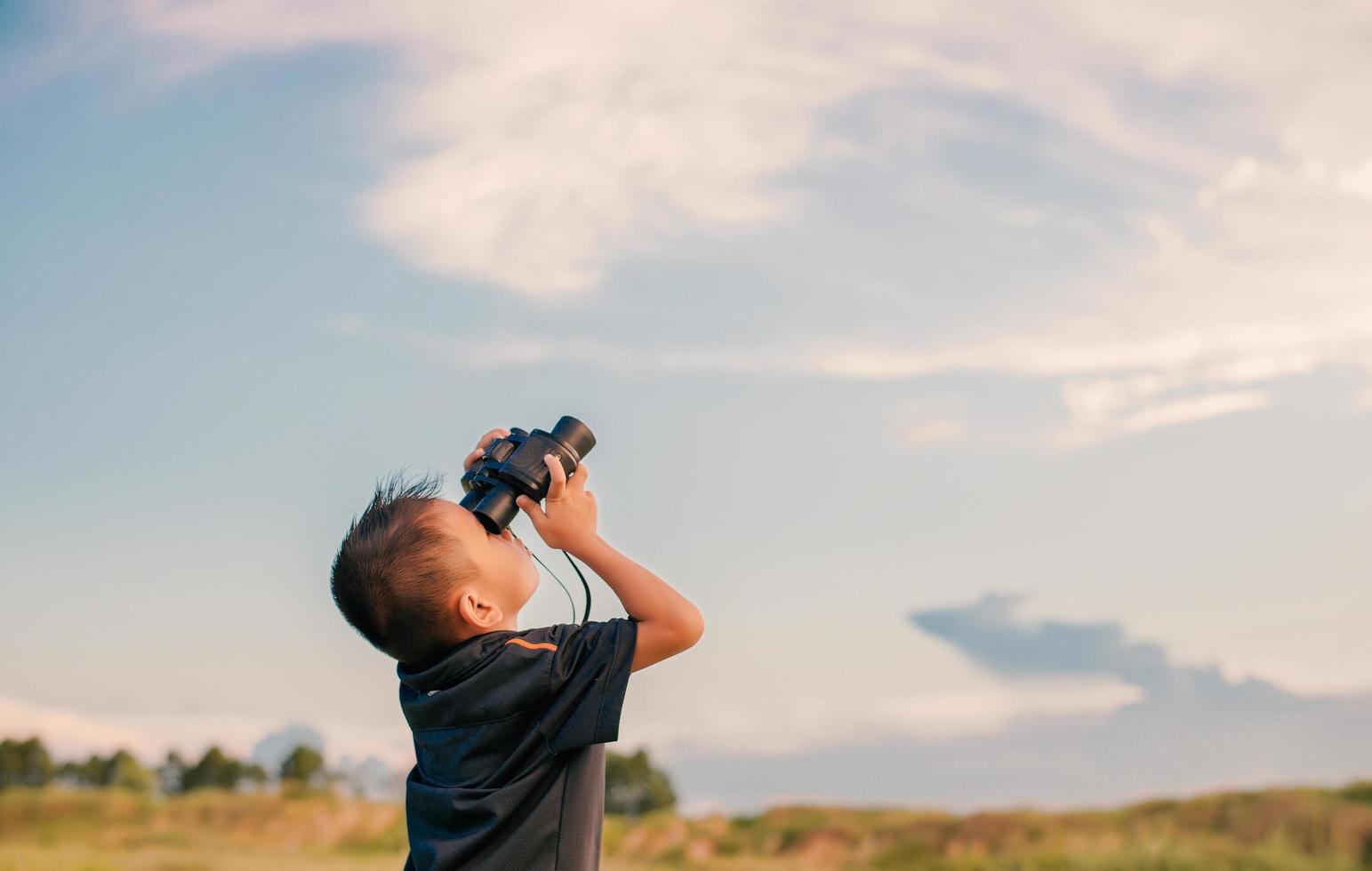 Niño feliz jugando con binoculares en la pradera foto