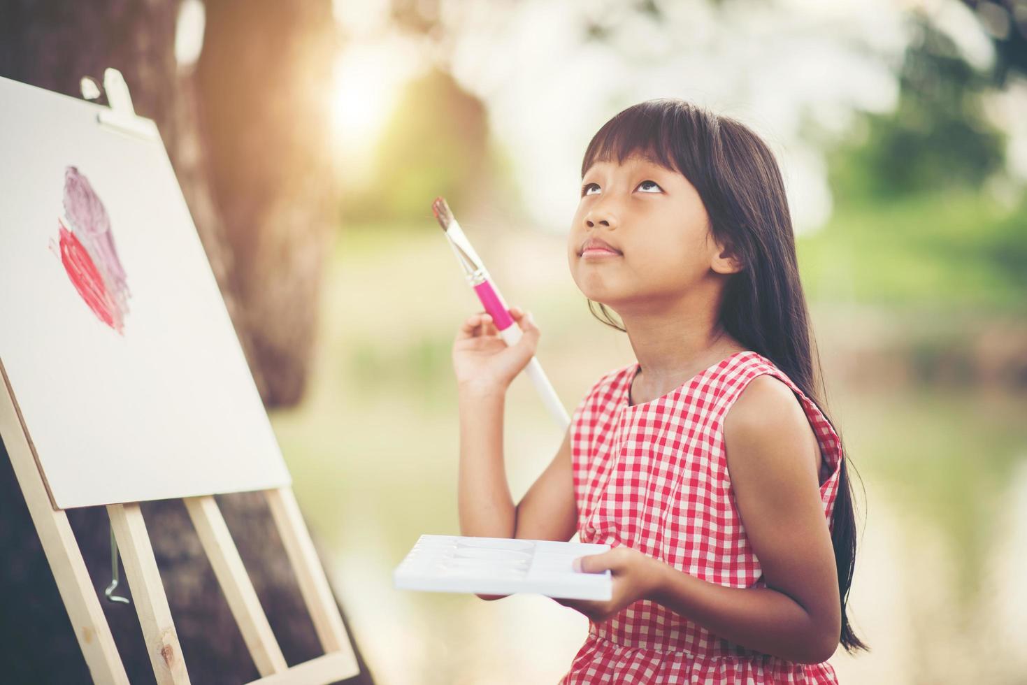 Little girl artist painting a picture in the park photo