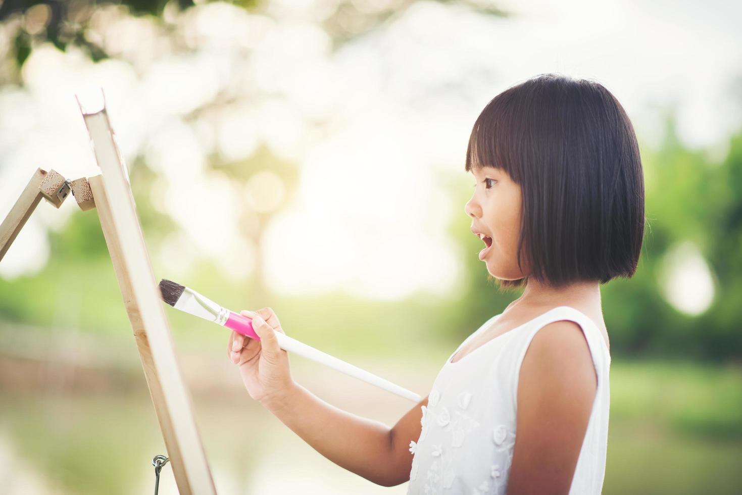 Little girl artist painting a picture in the park photo