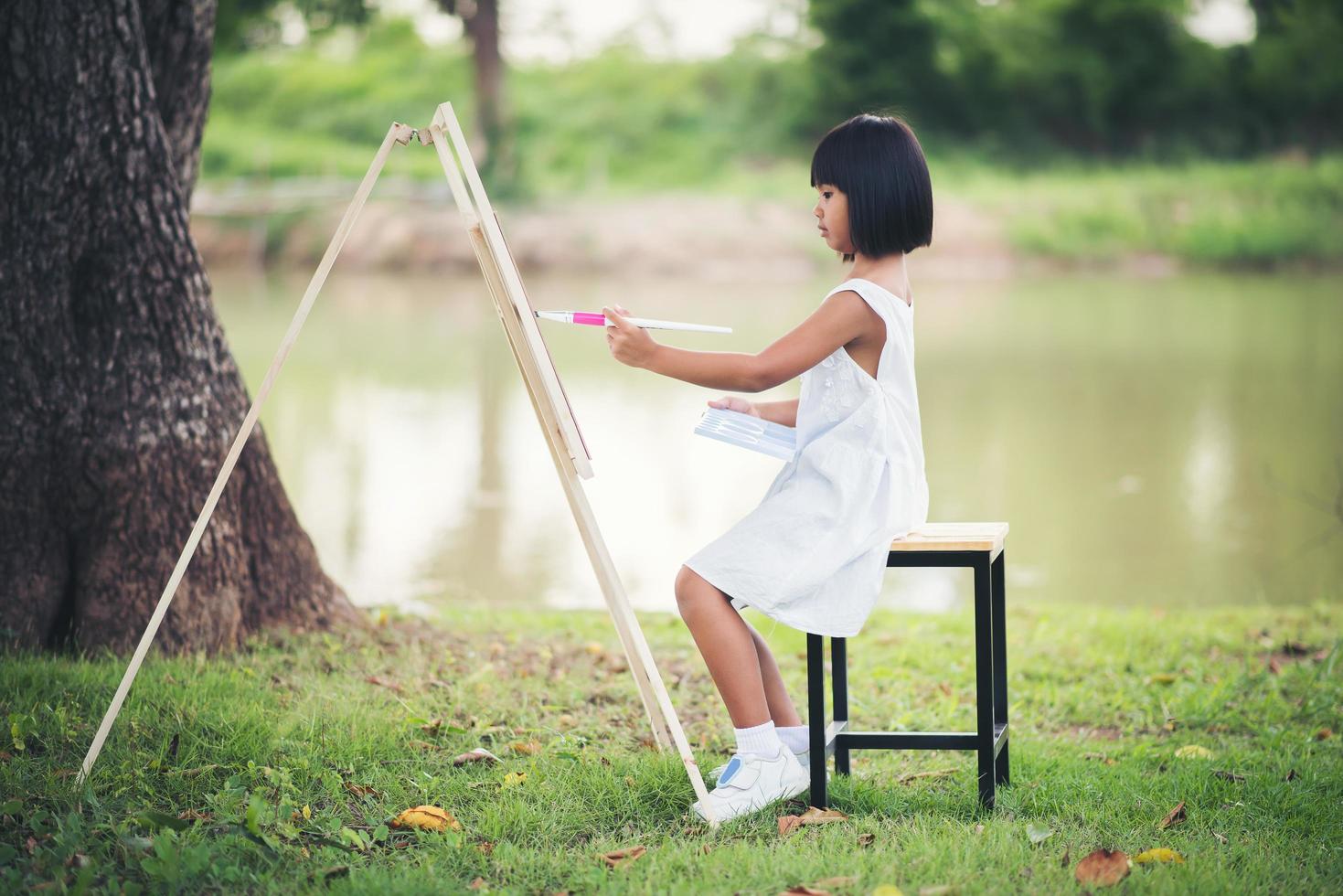 niña artista pintando un cuadro en el parque foto