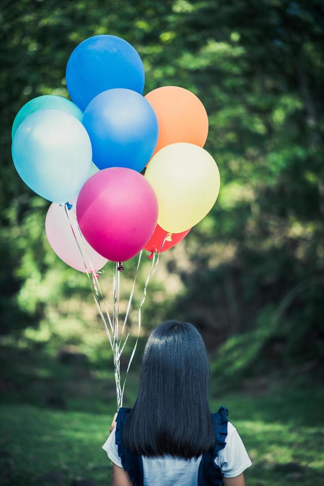 Young girl holding colorful balloons in nature photo