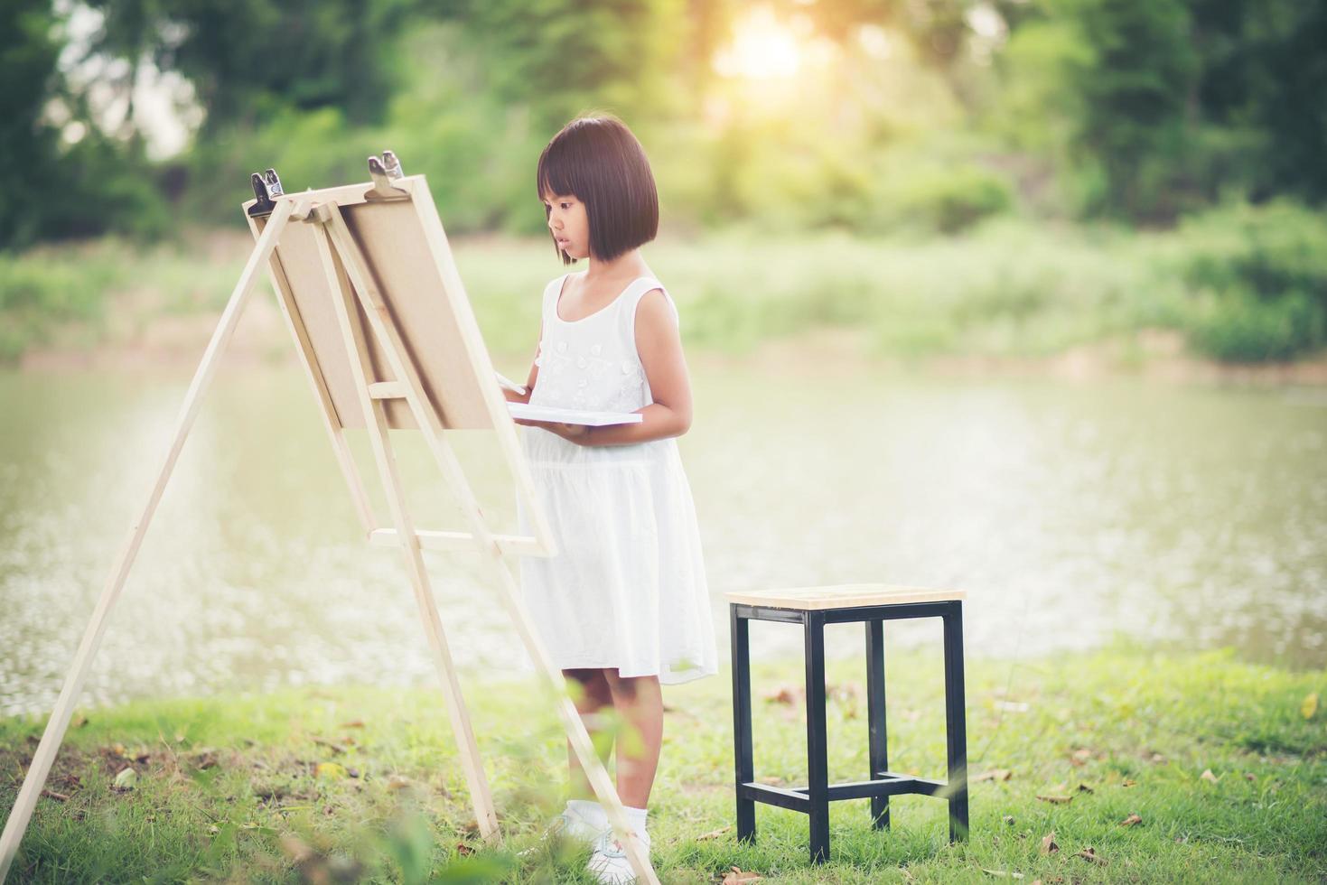 niña artista pintando un cuadro en el parque foto