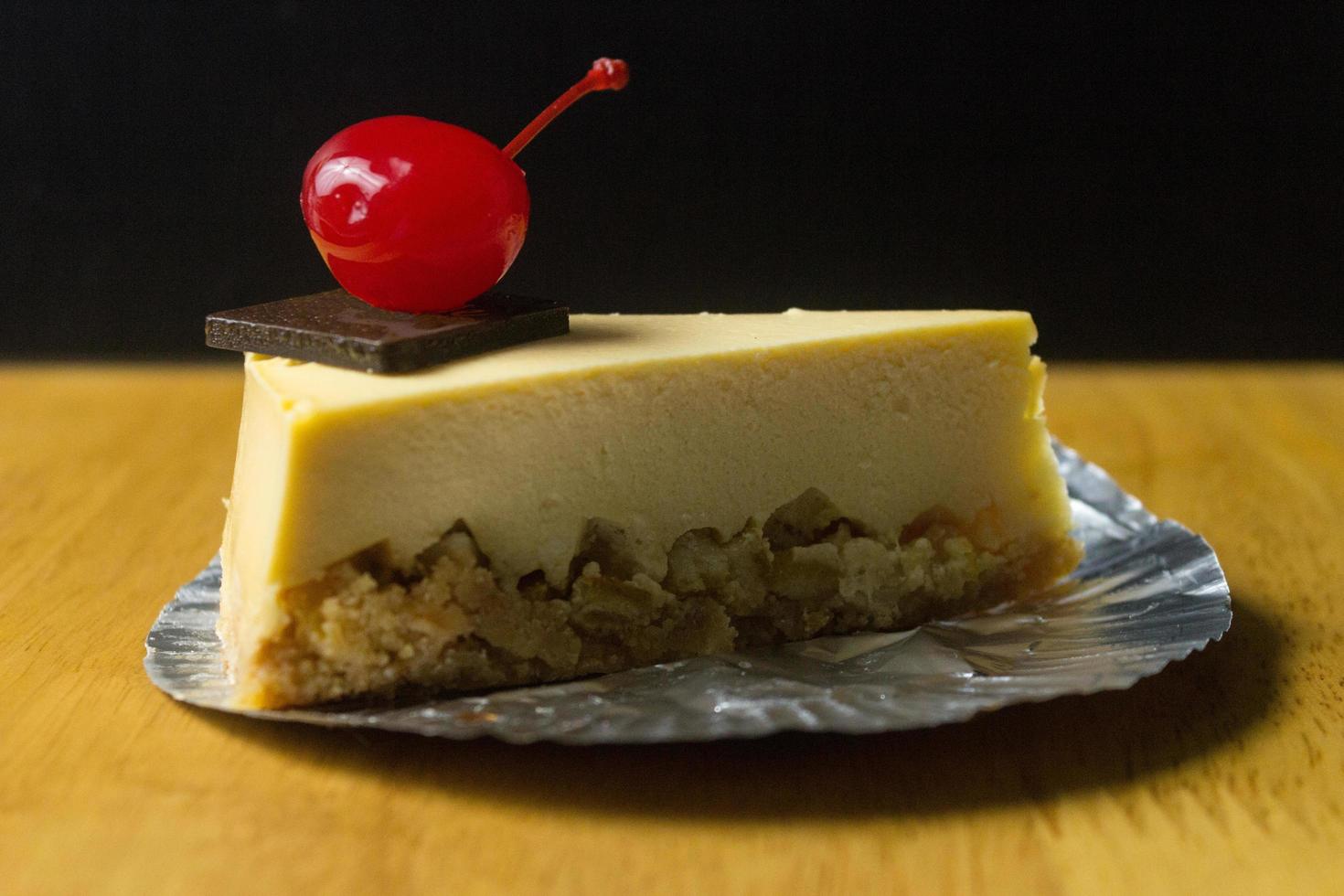 Slice of cheesecake with chocolate and cherry on wood table photo