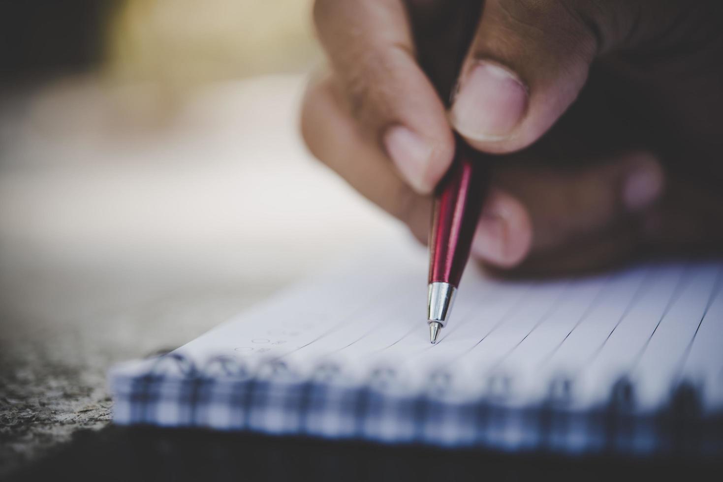 hombre escribiendo a mano en su cuaderno foto