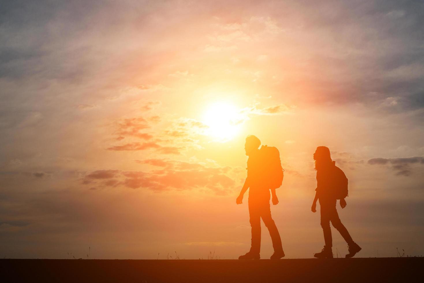 siluetas de dos excursionistas con mochilas disfrutando de la puesta de sol foto