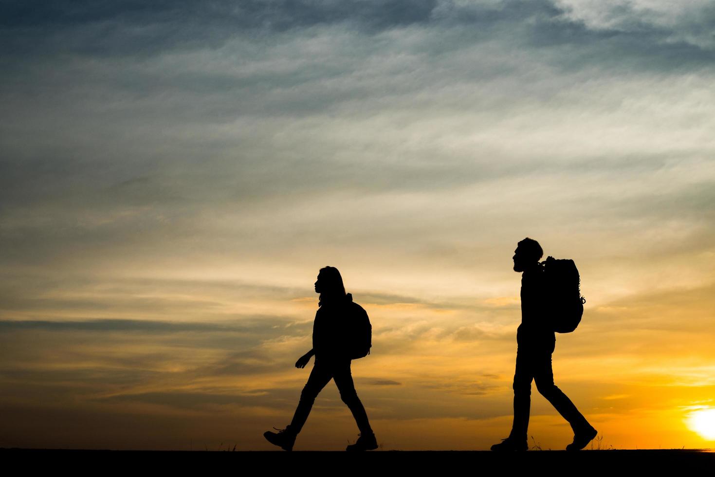 Silhouettes of two hikers with backpacks enjoying the sunset photo