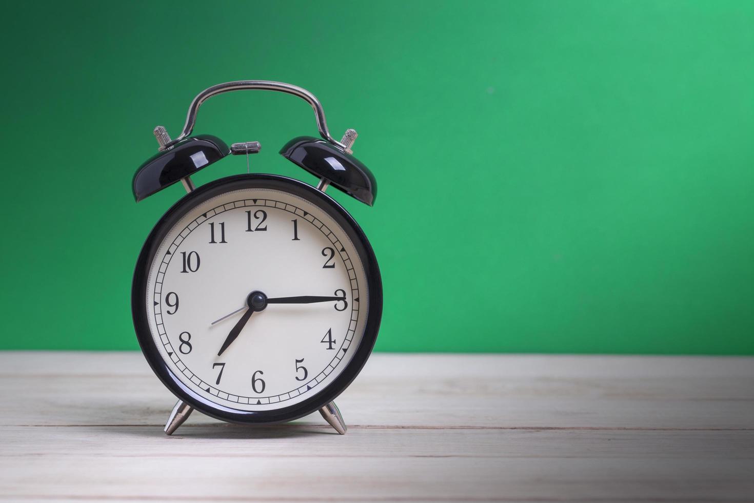 Alarm clock on desk with green background photo