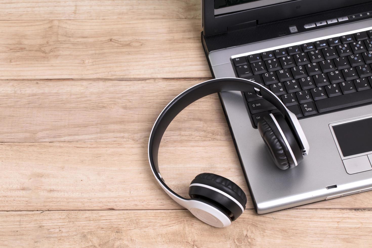 Auriculares y portátil en escritorio de madera foto