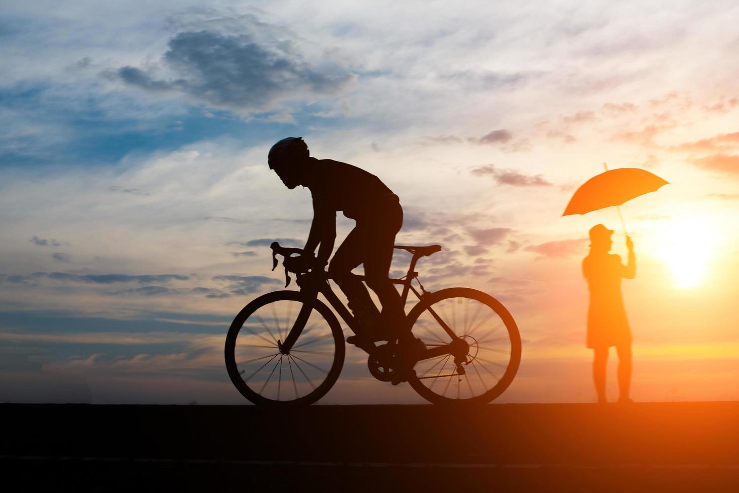 Young man rides a bicycle on sunset background photo
