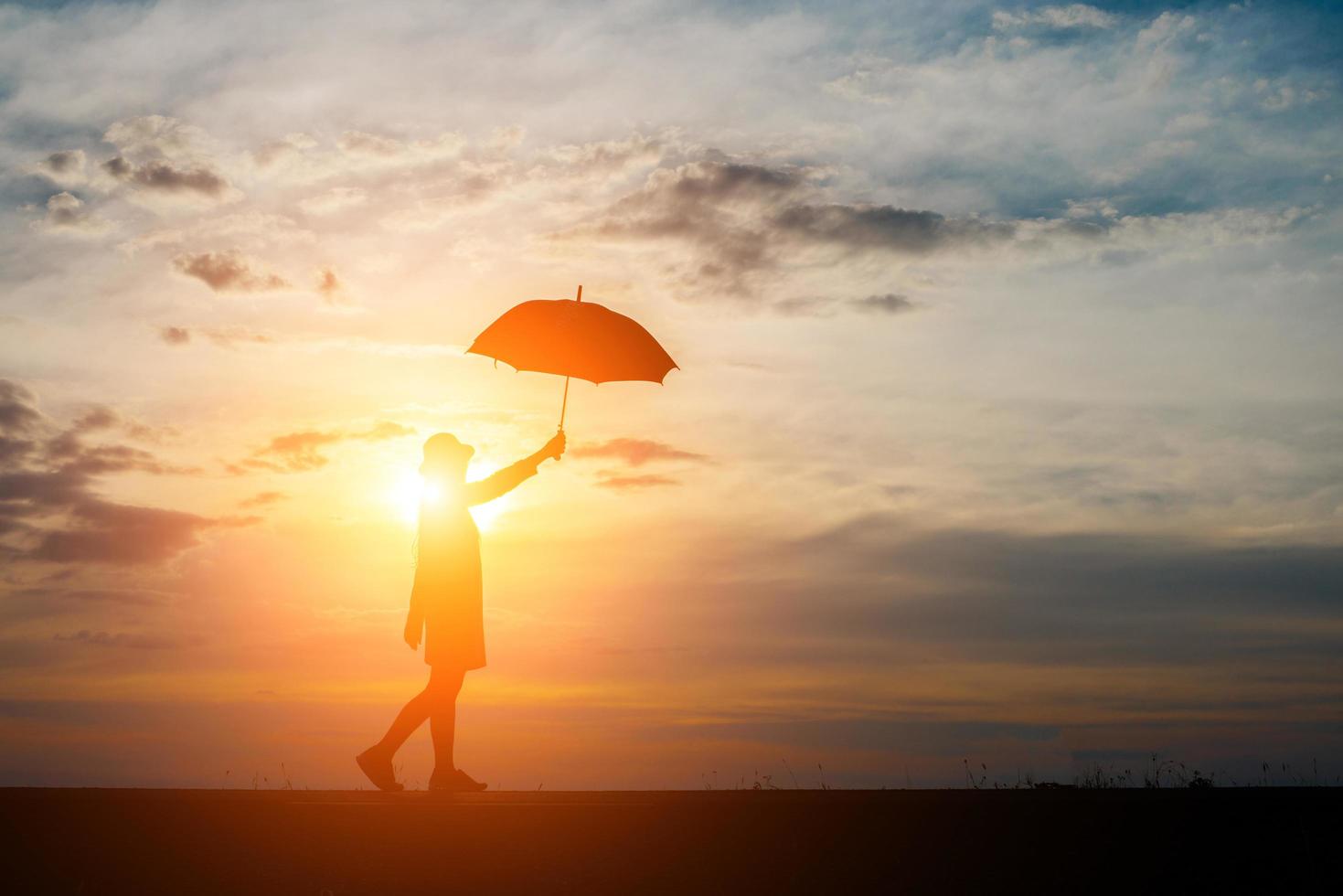 Silhouette of a woman holding an umbrella on the beach and sunset photo