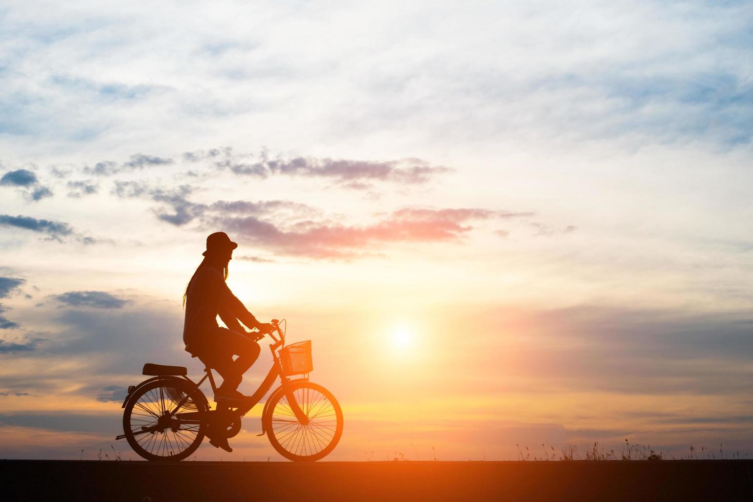 joven monta una bicicleta en el fondo del atardecer foto