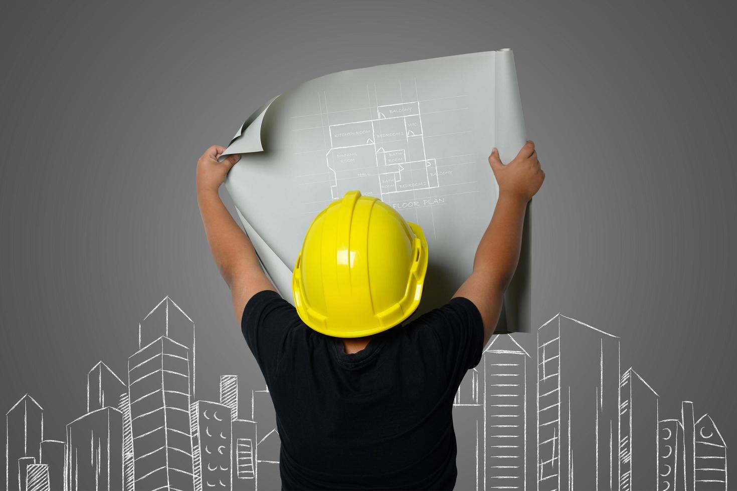 Young boy wearing a yellow engineer hat and house plan ideas on a blackboard photo