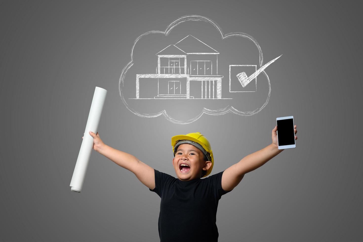 Young boy wearing a yellow engineer hat and house plan ideas on a blackboard photo