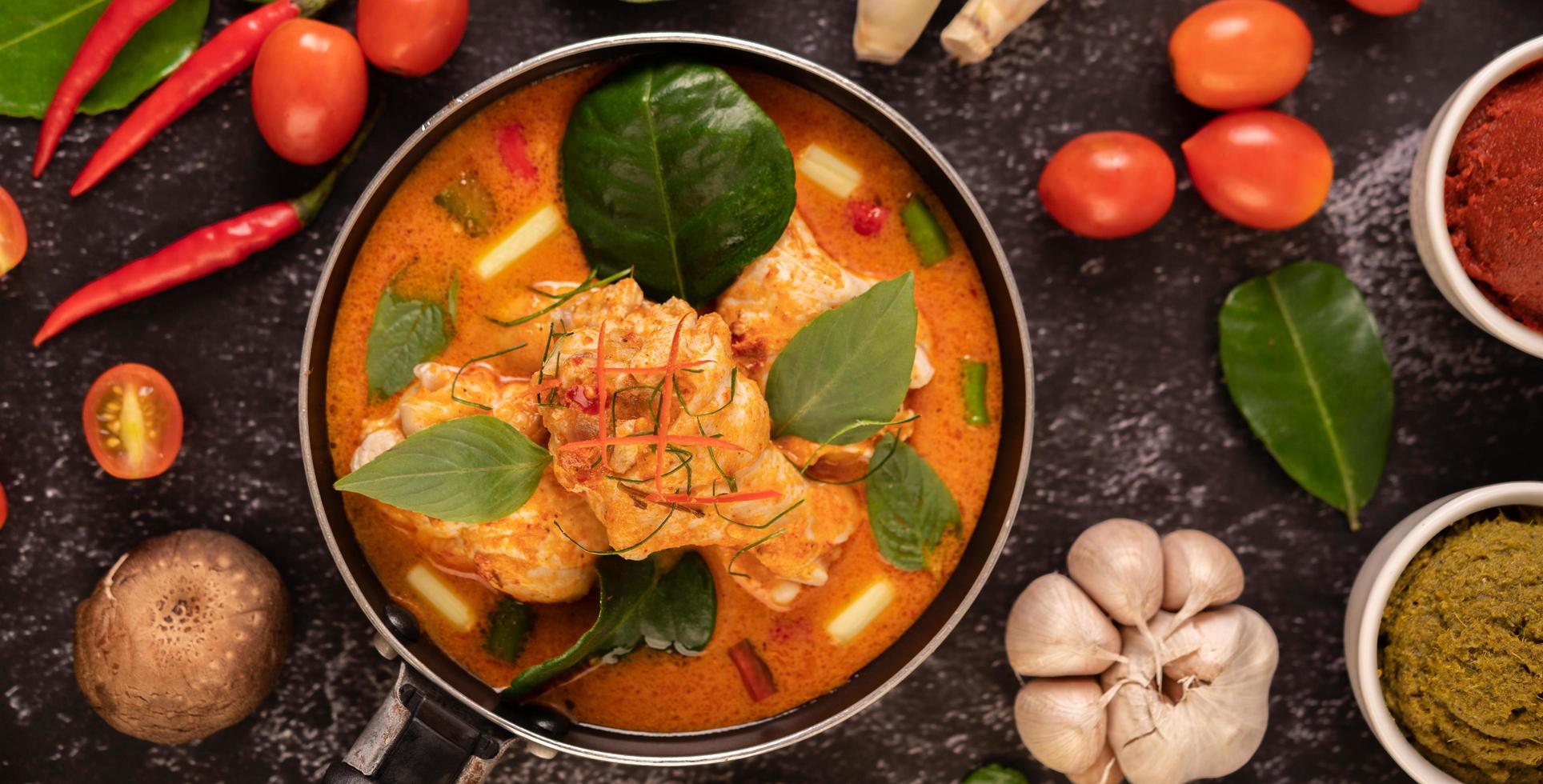 Chicken curry in a pan with lemongrass, kaffir lime leaves, tomatoes, lemon, and garlic photo