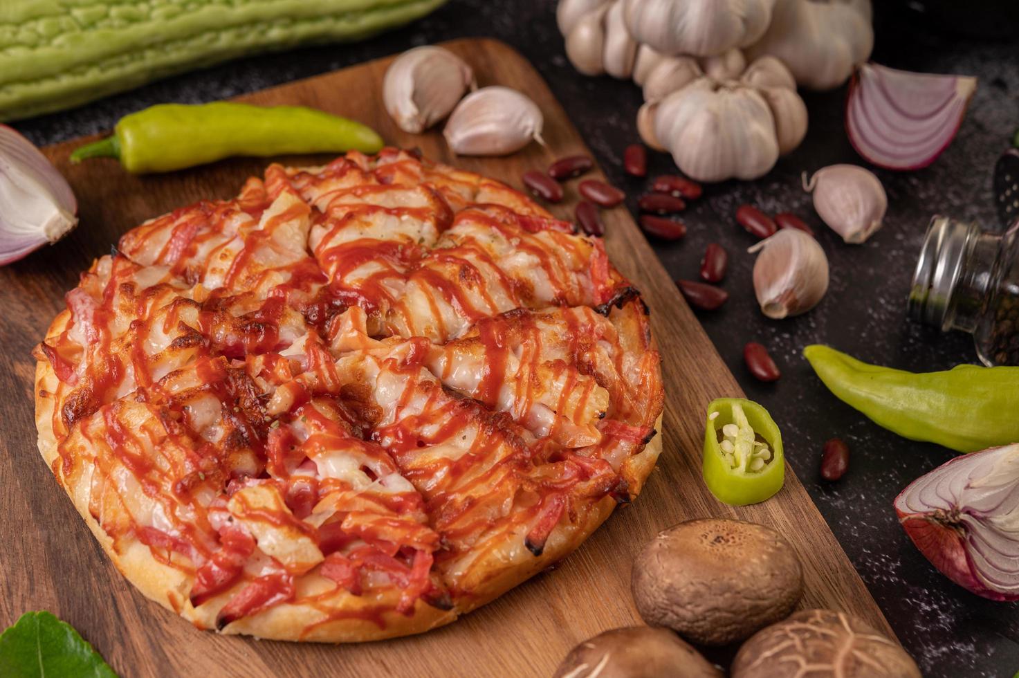 pizza en una tabla de madera con pimientos, ajo, chile y setas shiitake foto