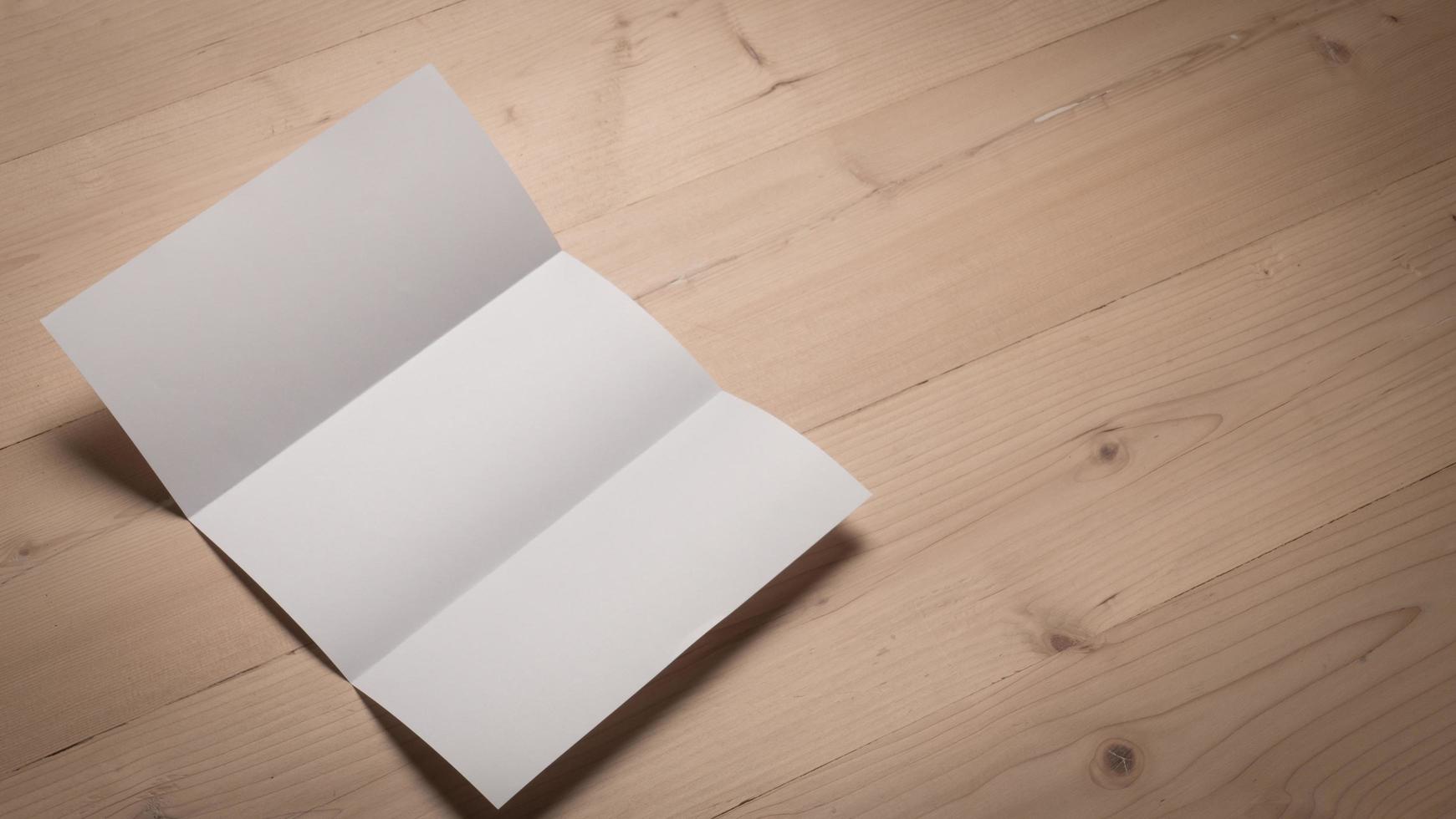 White blank folded paper on wooden table photo