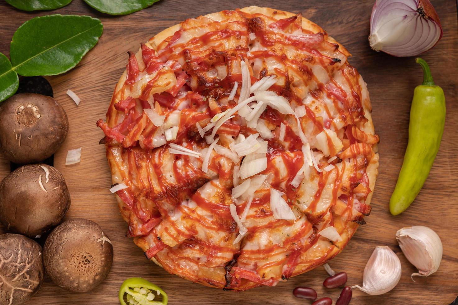 pizza en una tabla de madera con pimientos, ajo, chile y setas shiitake foto