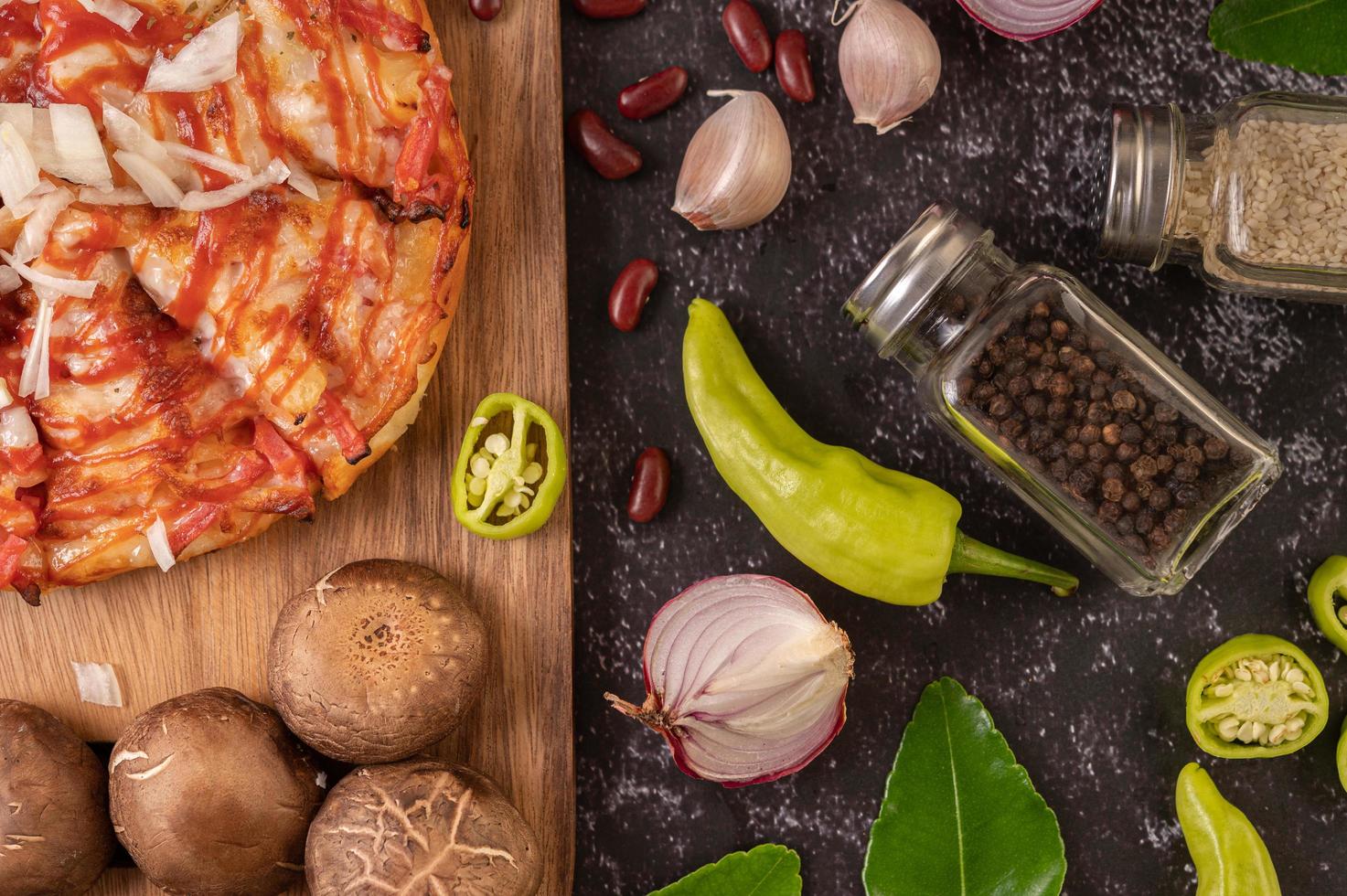 Pizza on a wooden board with bell peppers, garlic, chili and shiitake mushrooms photo