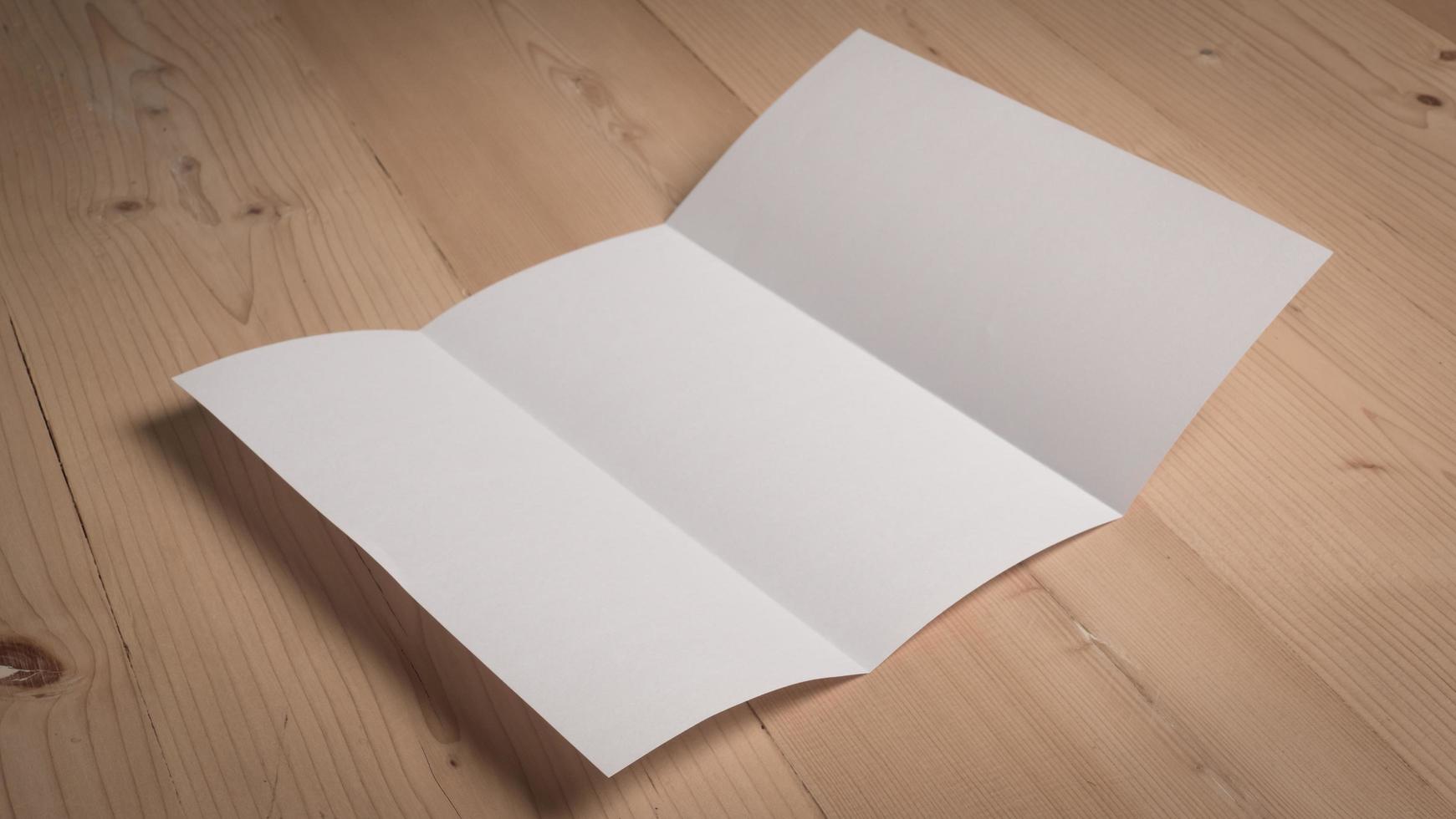 Papel doblado en blanco blanco sobre mesa de madera foto