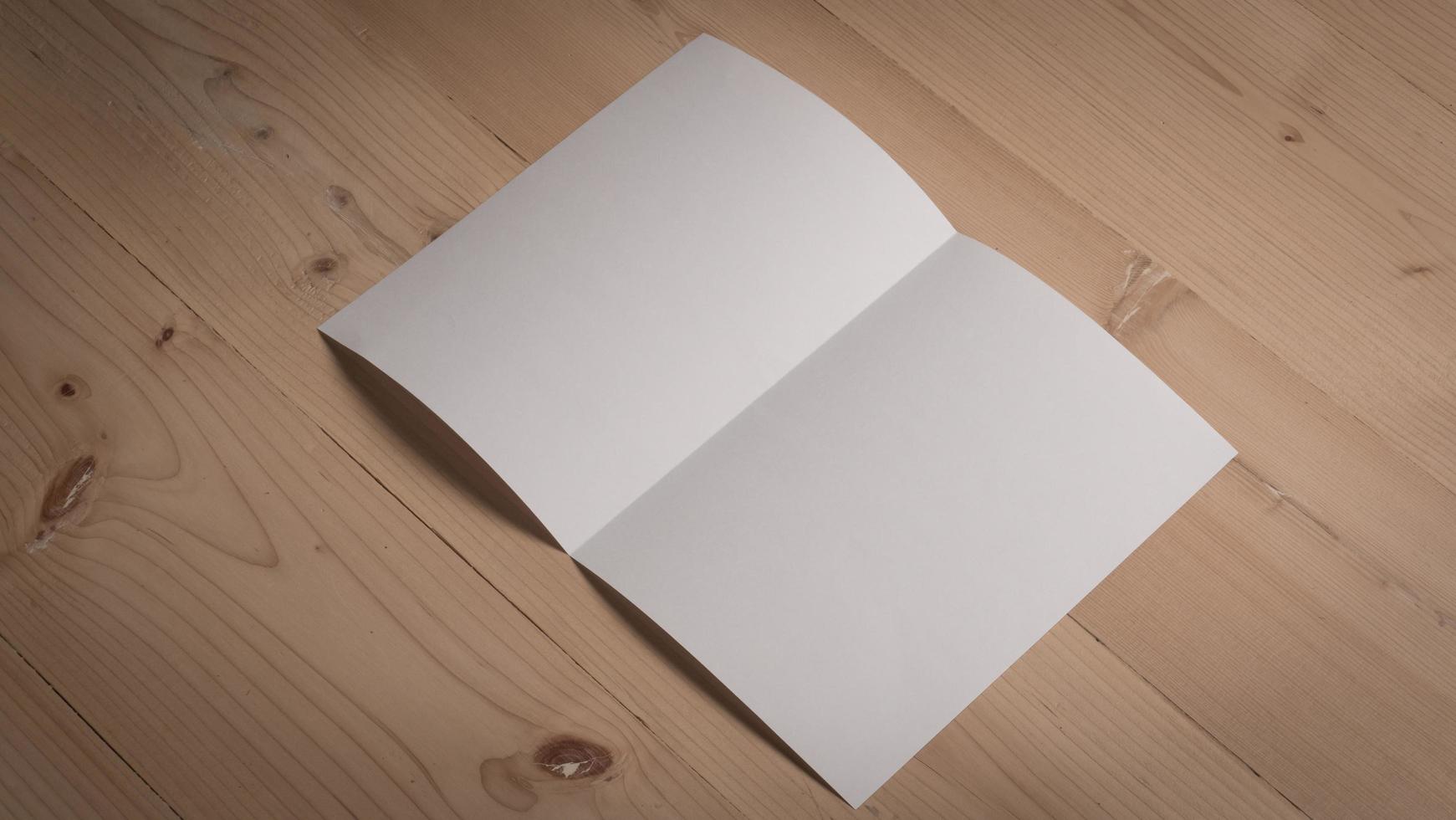 Papel doblado en blanco blanco sobre mesa de madera foto