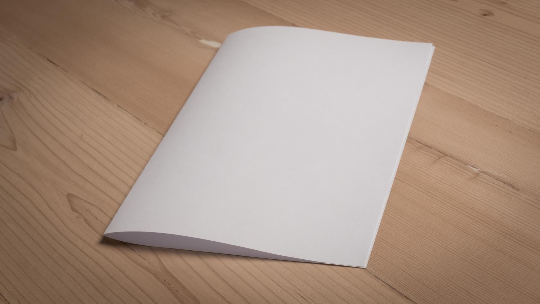 White blank folded paper on wooden table photo