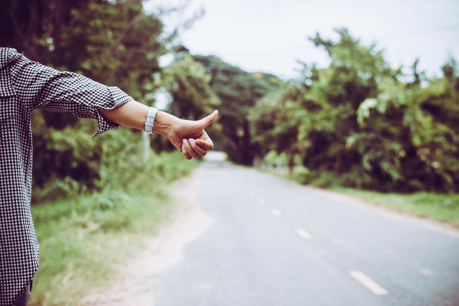 Mujer joven haciendo autostop junto a una carretera foto