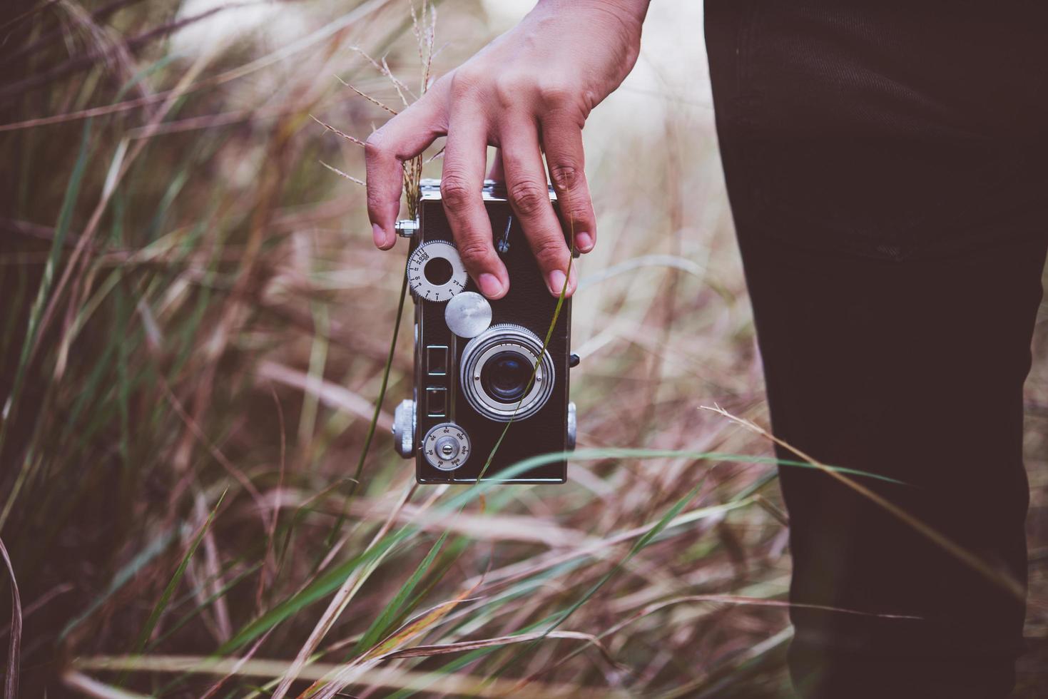 Close-up of a young woman's hand holding a retro camera in a field photo