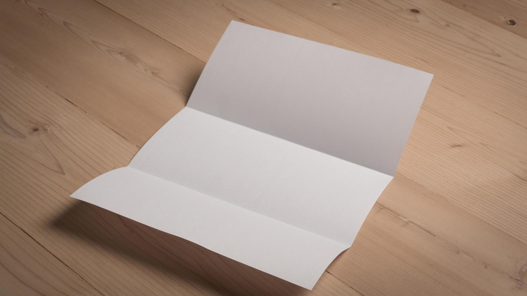 White blank folded paper on wooden table photo