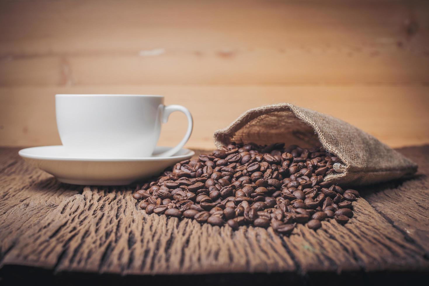 Coffee cup with coffee beans on a wood table photo