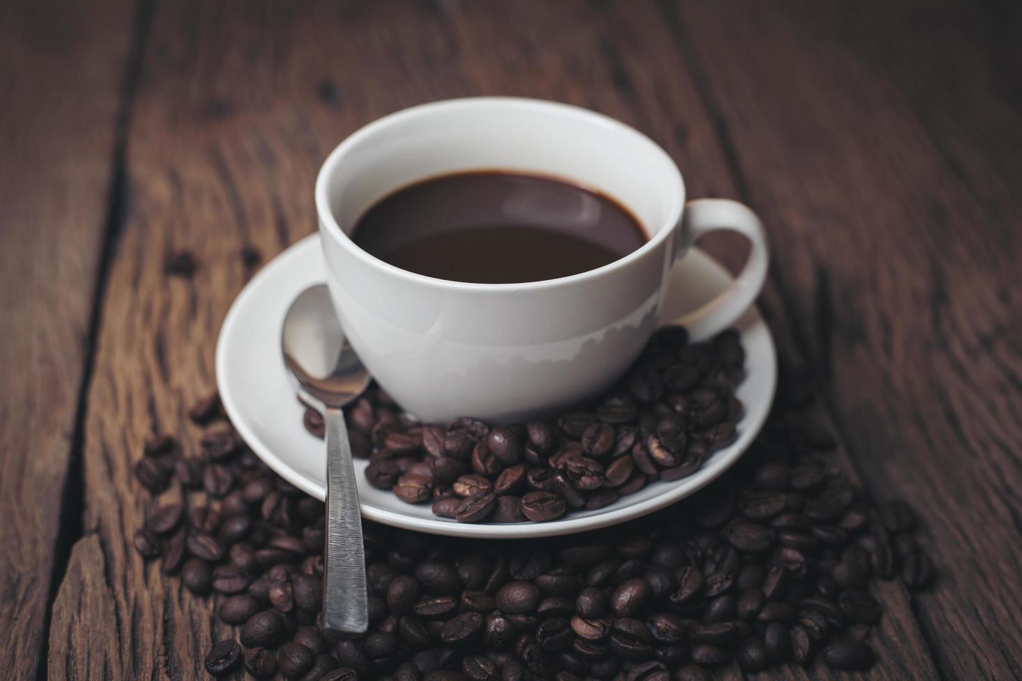 Coffee cup with coffee beans on a wood table photo