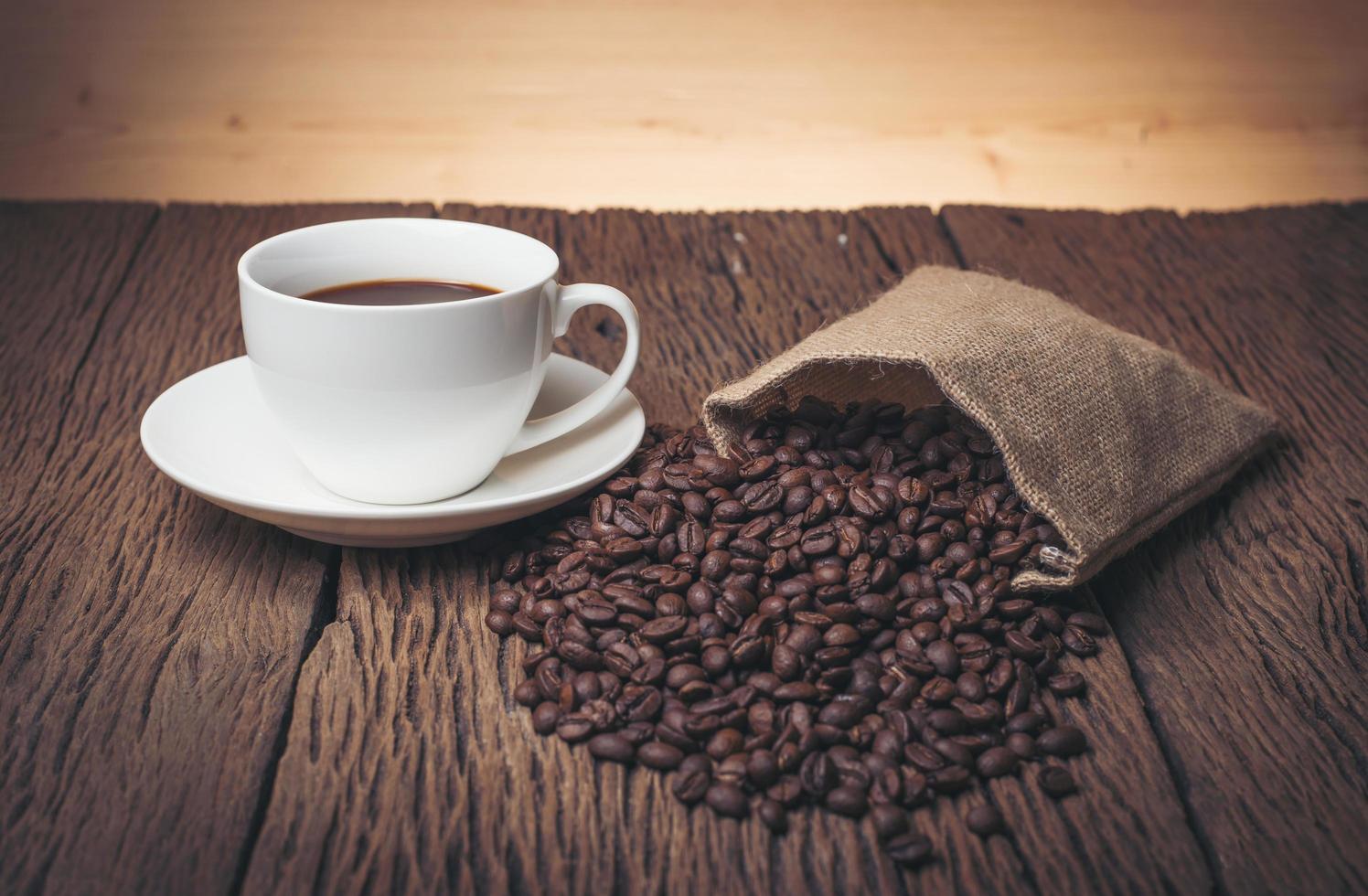 Coffee cup with coffee beans on a wood table photo