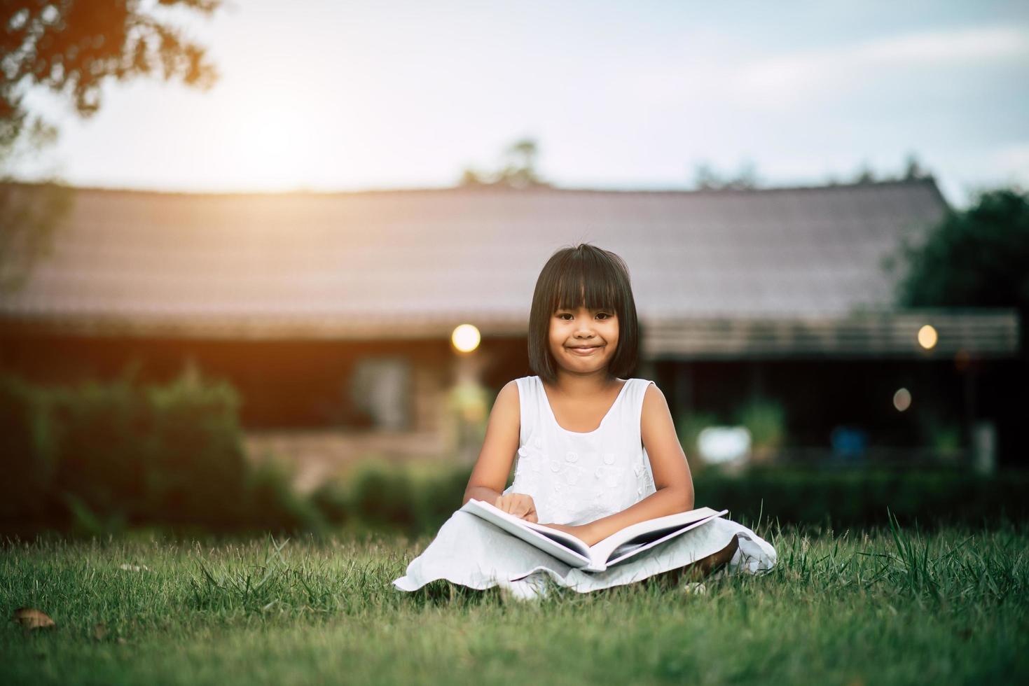 niña leyendo un libro en el jardín de su casa afuera foto