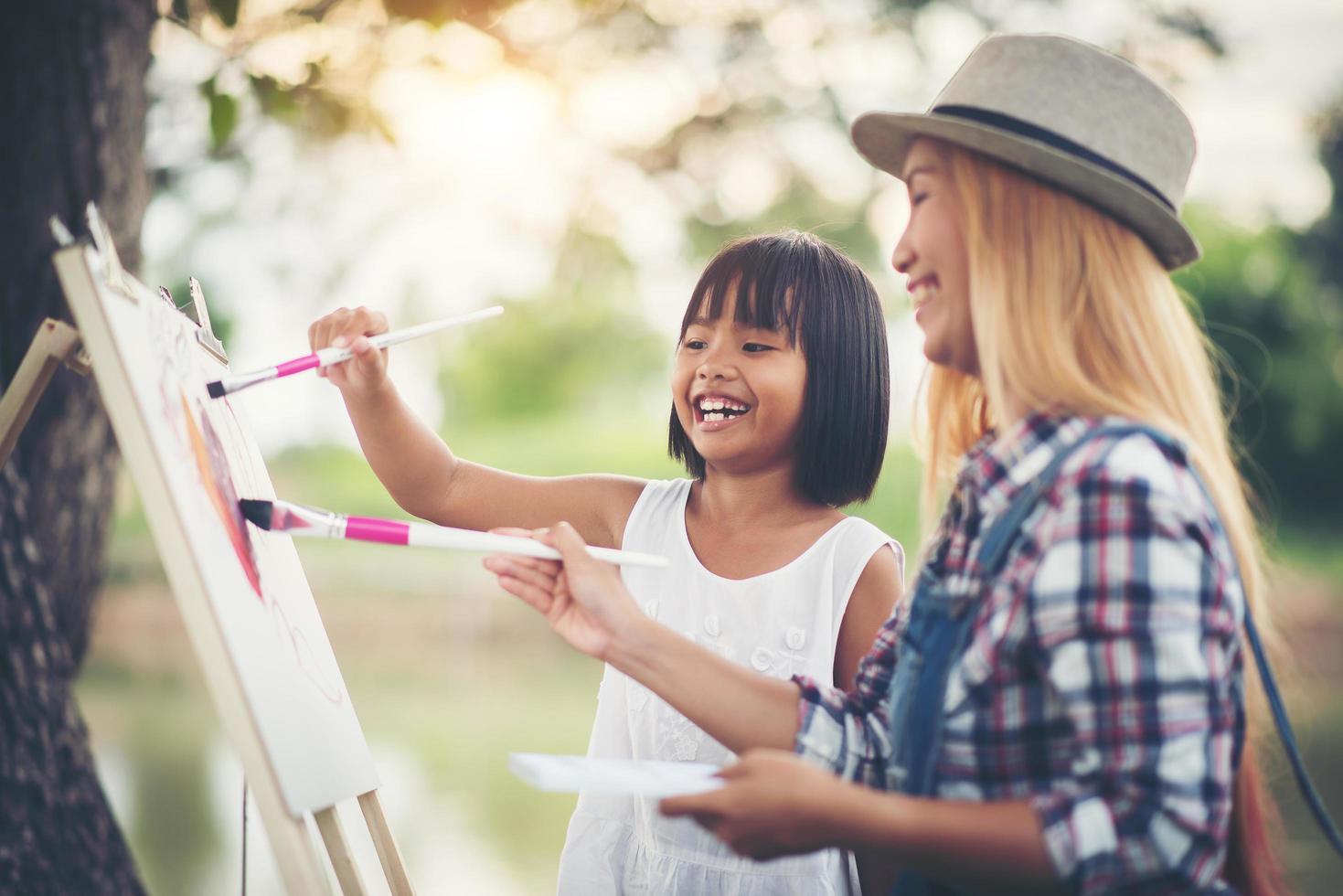 Mother and daughters drawing pictures together in a park photo