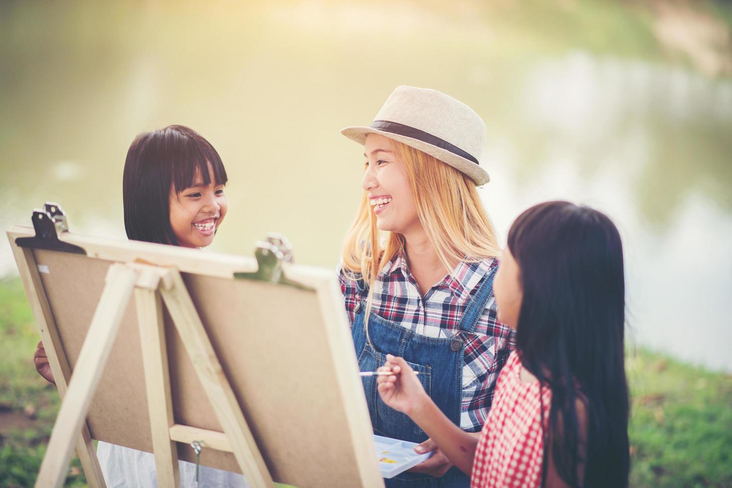 madre e hijas haciendo dibujos juntos en un parque foto