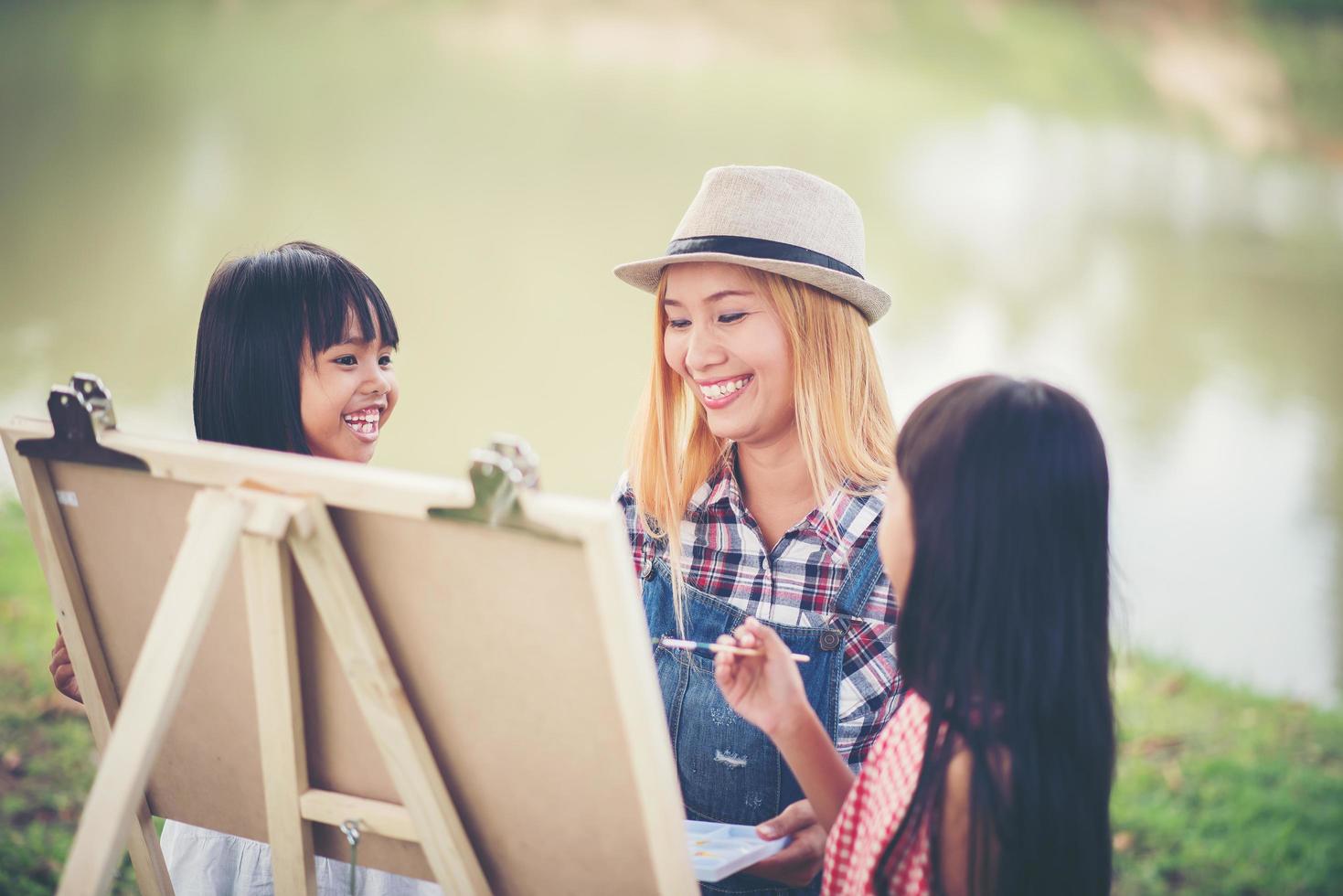 Mother and daughters drawing pictures together in a park photo