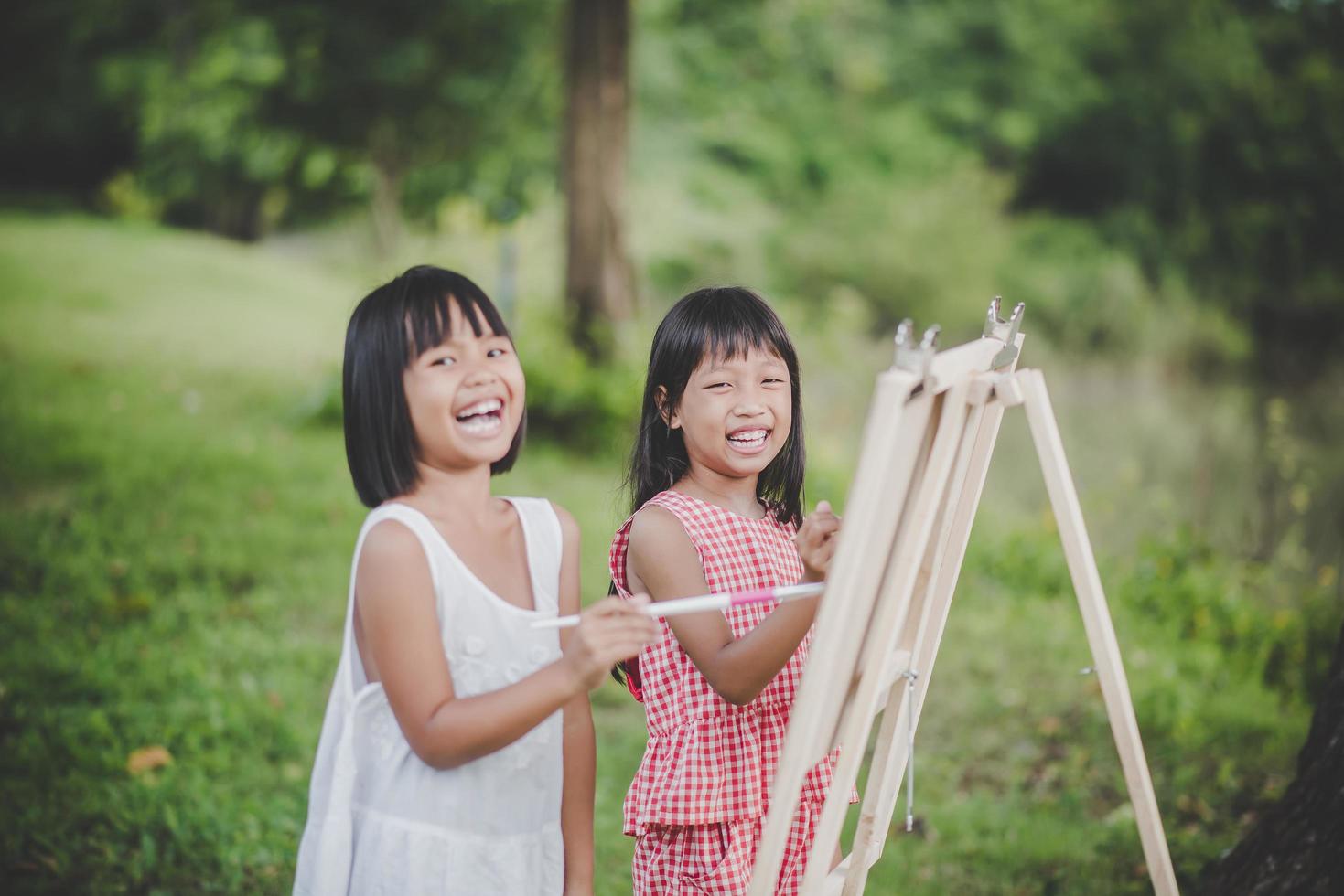 dos niñas pintores dibujando arte en el parque foto