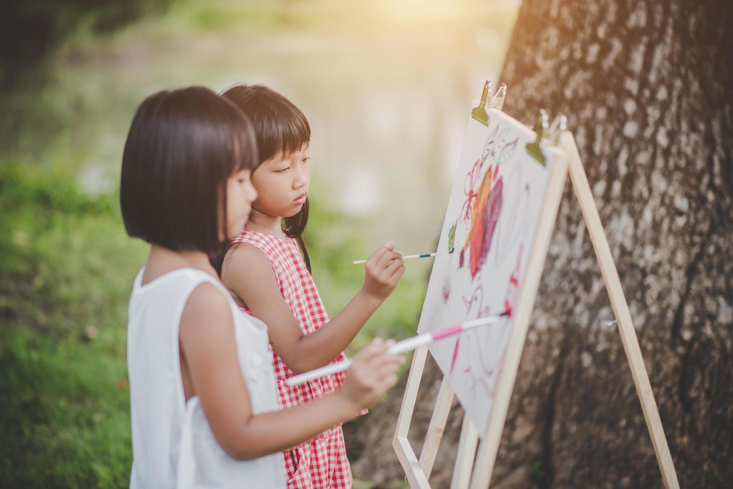 dos niñas pintores dibujando arte en el parque foto