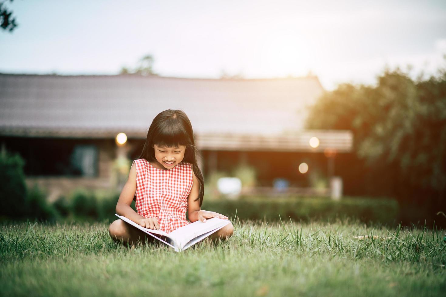 niña leyendo un libro en el jardín de su casa afuera foto