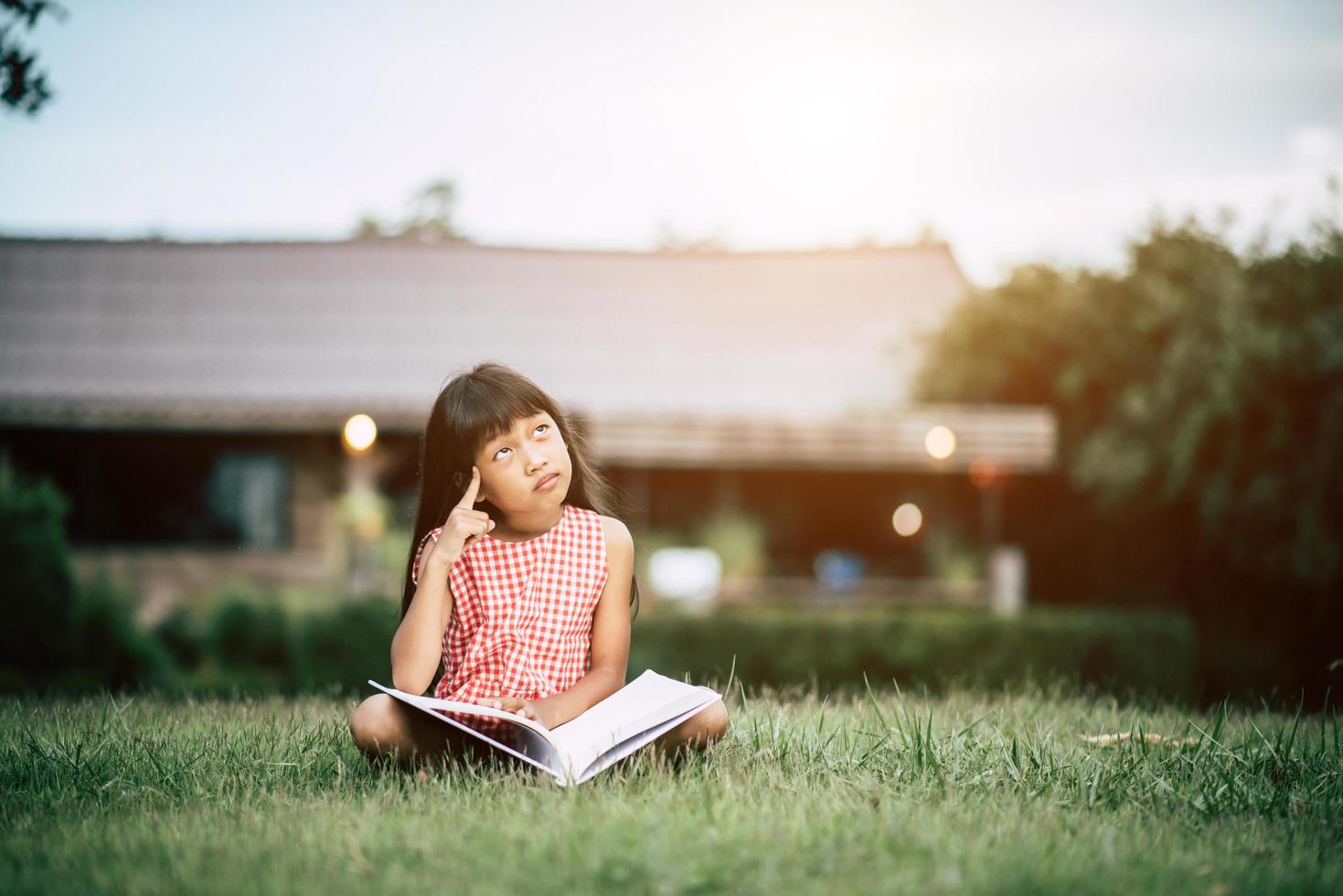 Little girl reading a book in her house garden outside photo