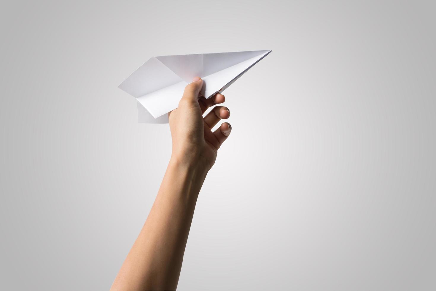 Mano de mujer sosteniendo un avión de papel aislado sobre fondo blanco. foto
