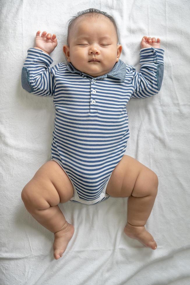 un bebé con una camisa a rayas durmiendo en la cama foto