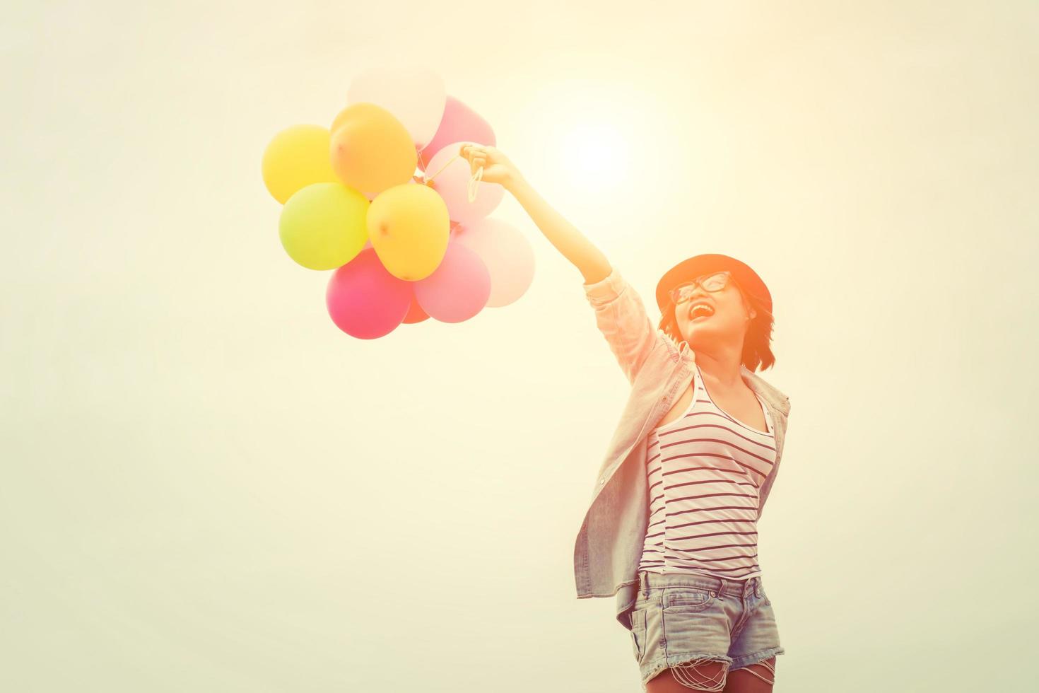 mujer joven inconformista sosteniendo globos debajo del cielo foto