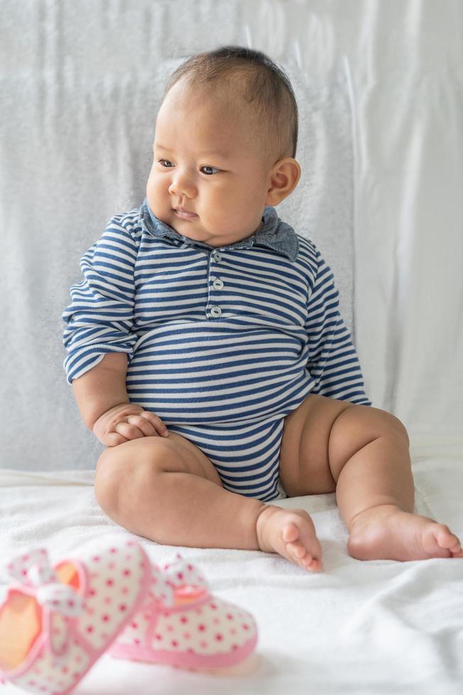 A baby learning to sit on a white bed photo