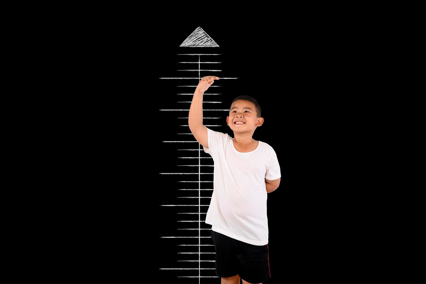 Young boy measures his height with the blackboard photo