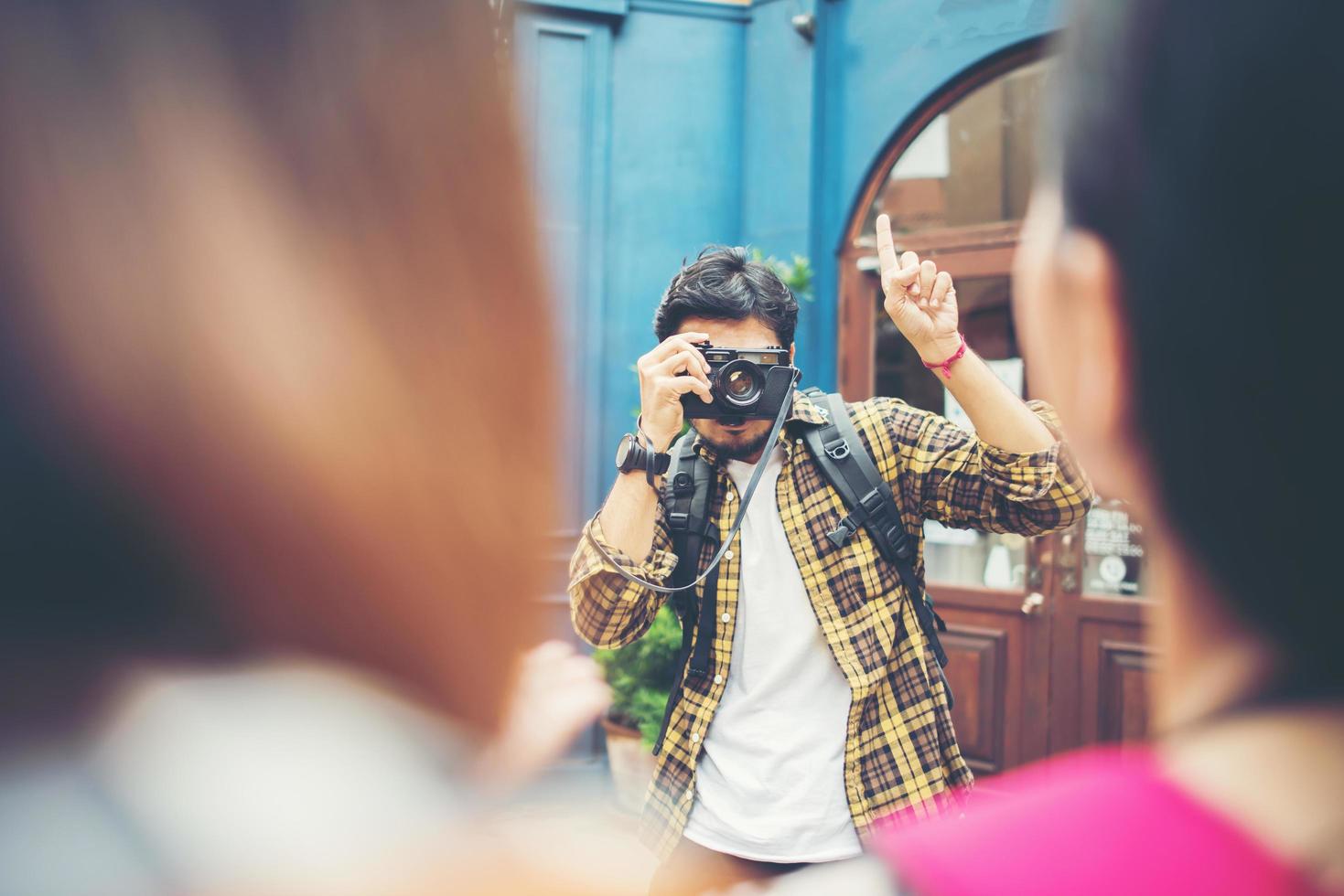 Young man taking pics of his friends while traveling in urban area together photo