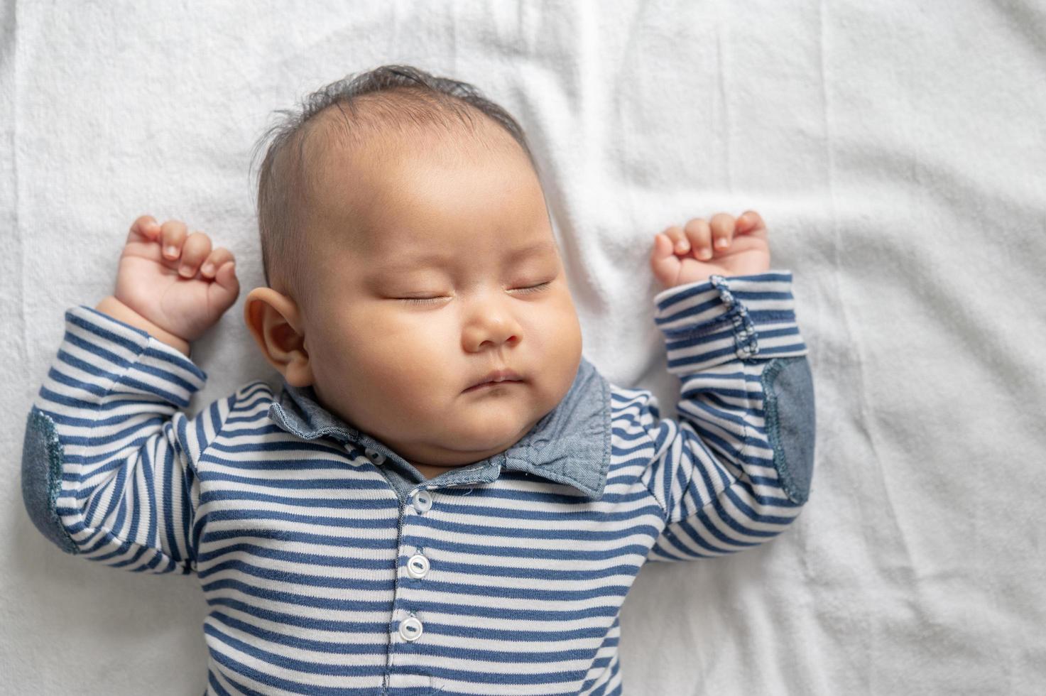 un bebé con una camisa a rayas durmiendo en la cama foto