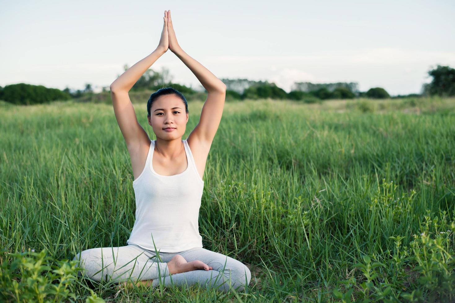Young yoga woman sits in meditation in the meadows photo