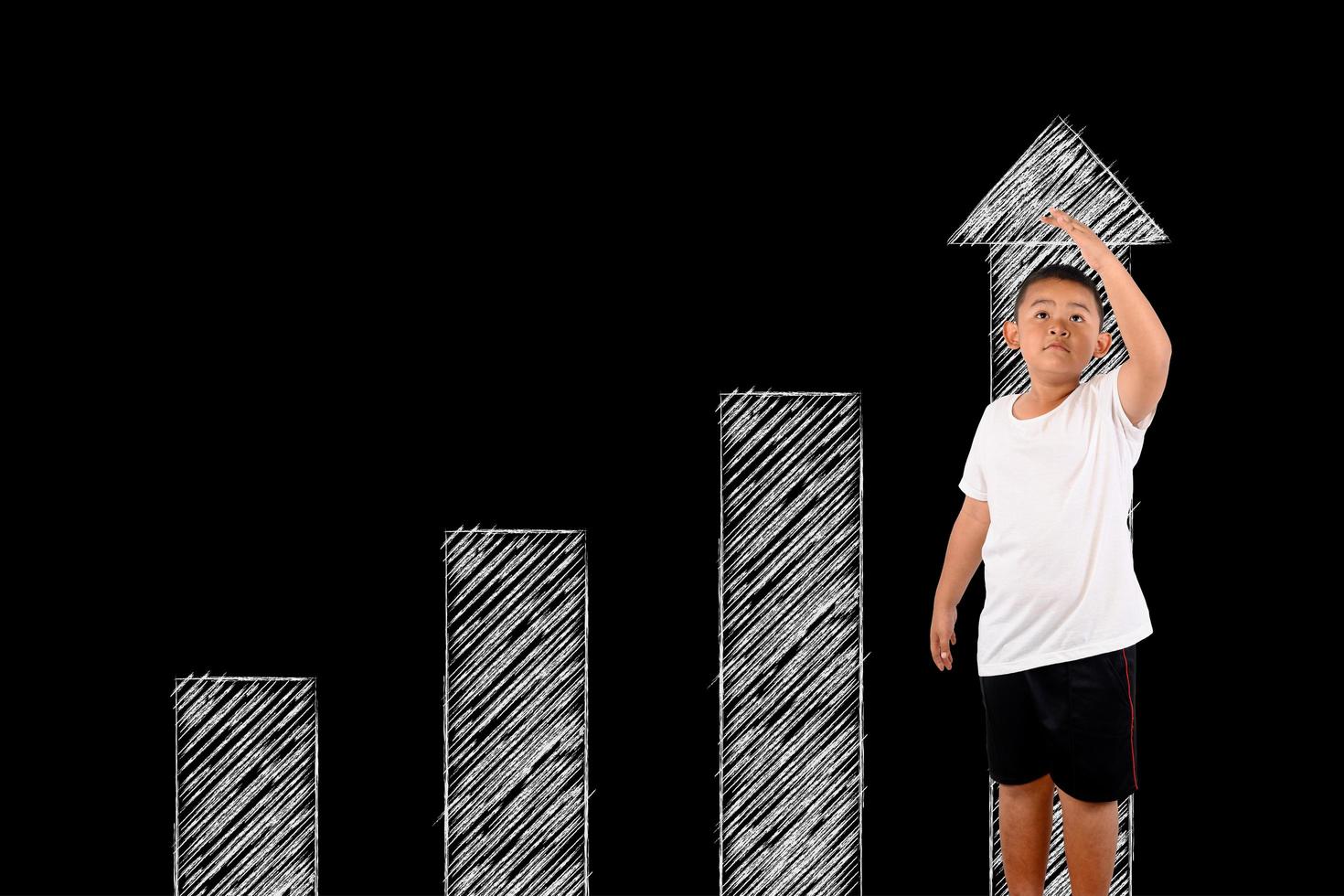 Young boy measures his height with the blackboard photo