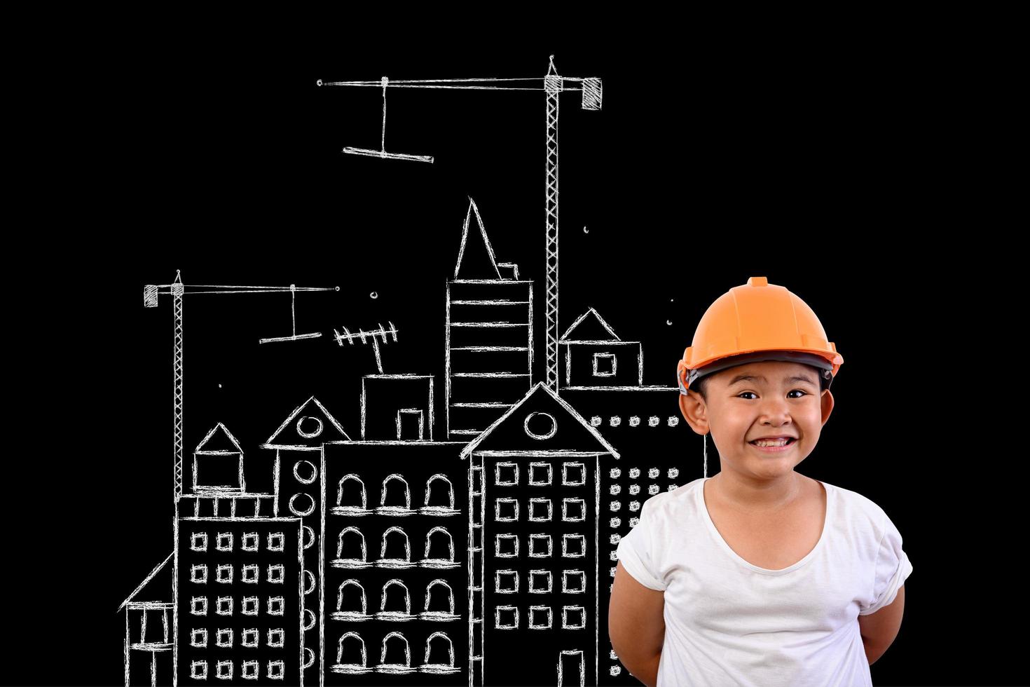 Young boy wearing an engineer hat and a house plan on a blackboard photo