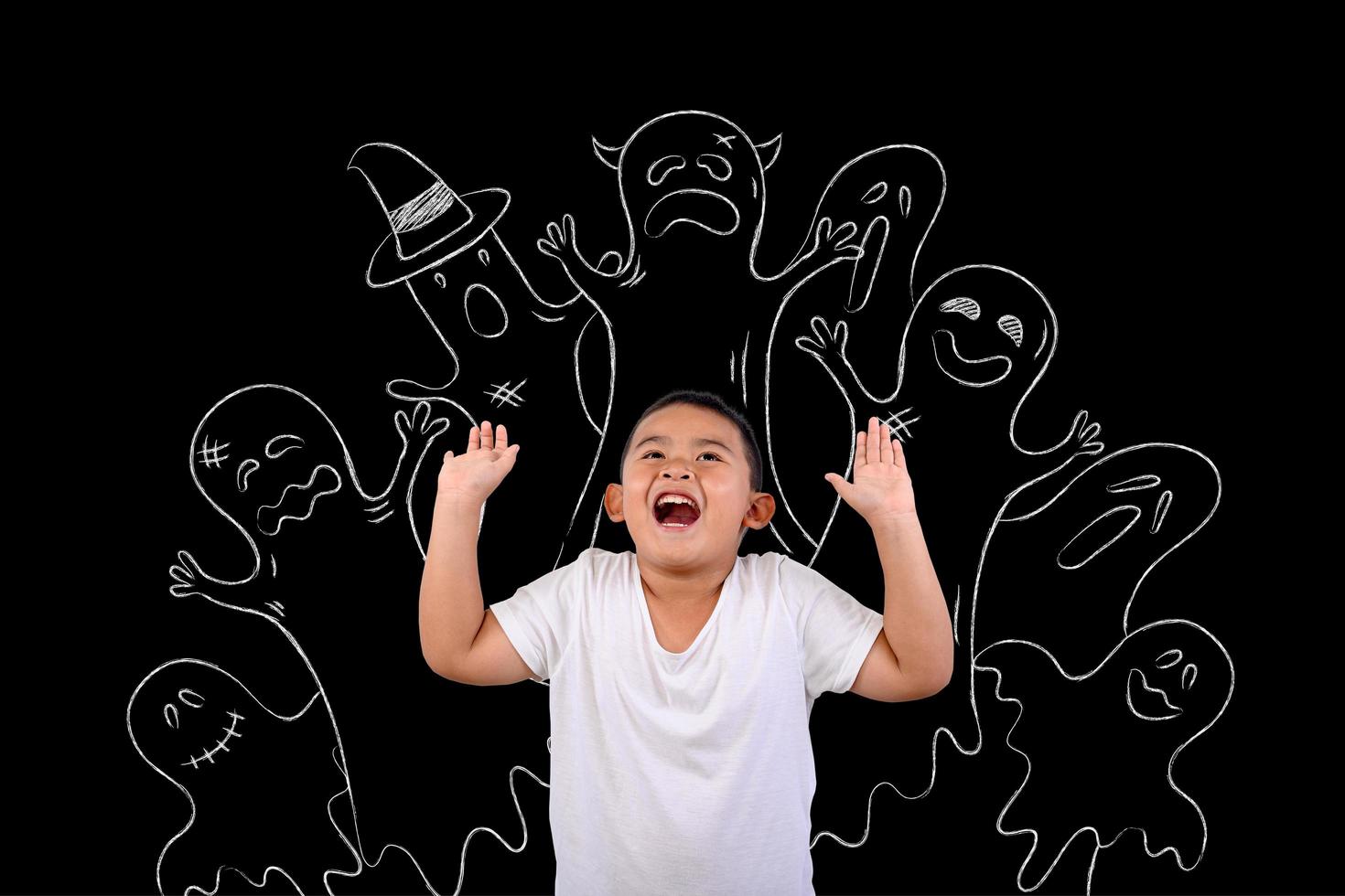 Young boy stands scared of ghosts drawn on blackboard photo